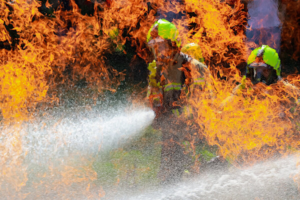 Zwei Feuerwehrleute hinter Flammen