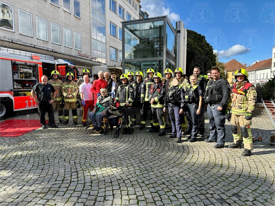 Gemeinsames Gruppenbild: Befreite Dame, Aufzugsmonteur, Polizei, Feuerwehr