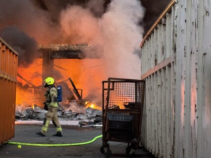 Einsatzkraft mit Schutzausrüstung vor der brennenden Lagerhalle