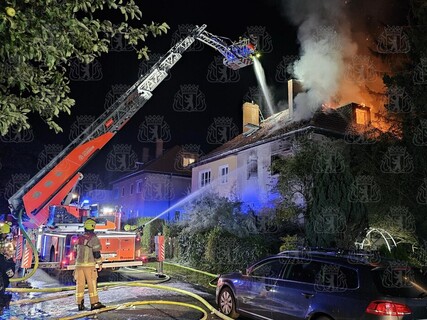 Brandbekämpfung über Drehleiter vor dem brennenden Haus. 