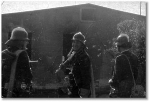 Drei Feuerwehrleute vor Lagerhalle